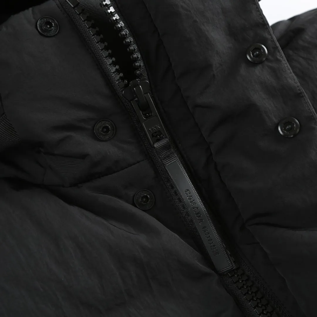 P740 Big Goose Logo Hooded Down Vest Fabric selection: The use of high-quality protective nylon fabric not only enhances the wear resistance of the surface, but also takes into account wind resistance, ensuring excellent performance in various harsh weather conditions.  90 national standard high-quality white duck down: selected high-loft down, weighing 170g, light and warm, with excellent temperature locking performance and good resilience.  Three-dimensional quilting process: Precision thread reinforcement to prevent velvet drilling and ensure that the fluffy and resilient elasticity lasts as new.  Details: Use polyester as the base for woven webbing, and use high-precision computer embroidery to decorate the brand letters on the webbing. The edges of the pattern are clear, the stitches are fine and even, and multiple layers of embroidery threads are stacked to enhance the three-dimensional effect. Accessories: One-to-one customized logo One-to-one customized zipper pendant One-to-one customized hem elastic buckle One-to-one customized snap button SIZE: S M L XL